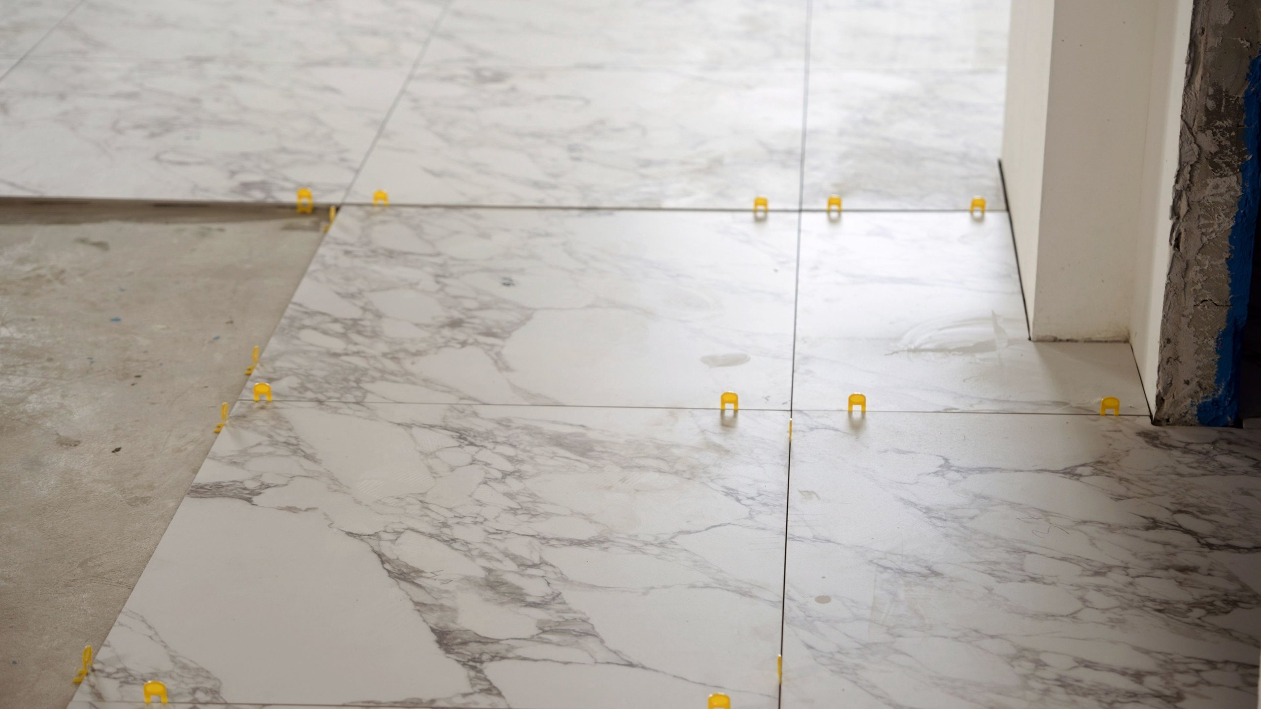 Professional tiler carefully positioning oversized marble tiles on floor