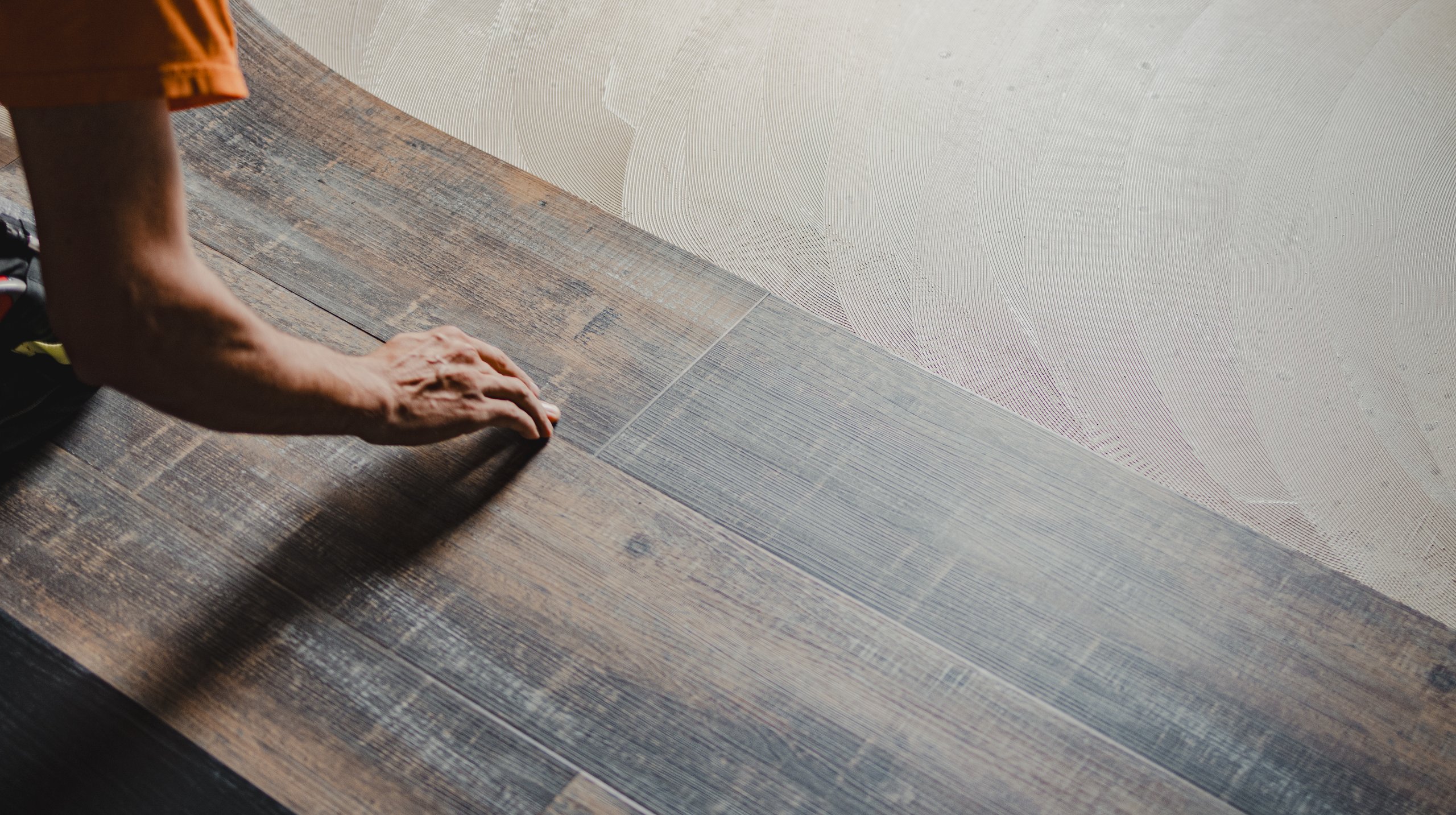 Professional builder laying vinyl tile flooring, using adhesive for perfect installation