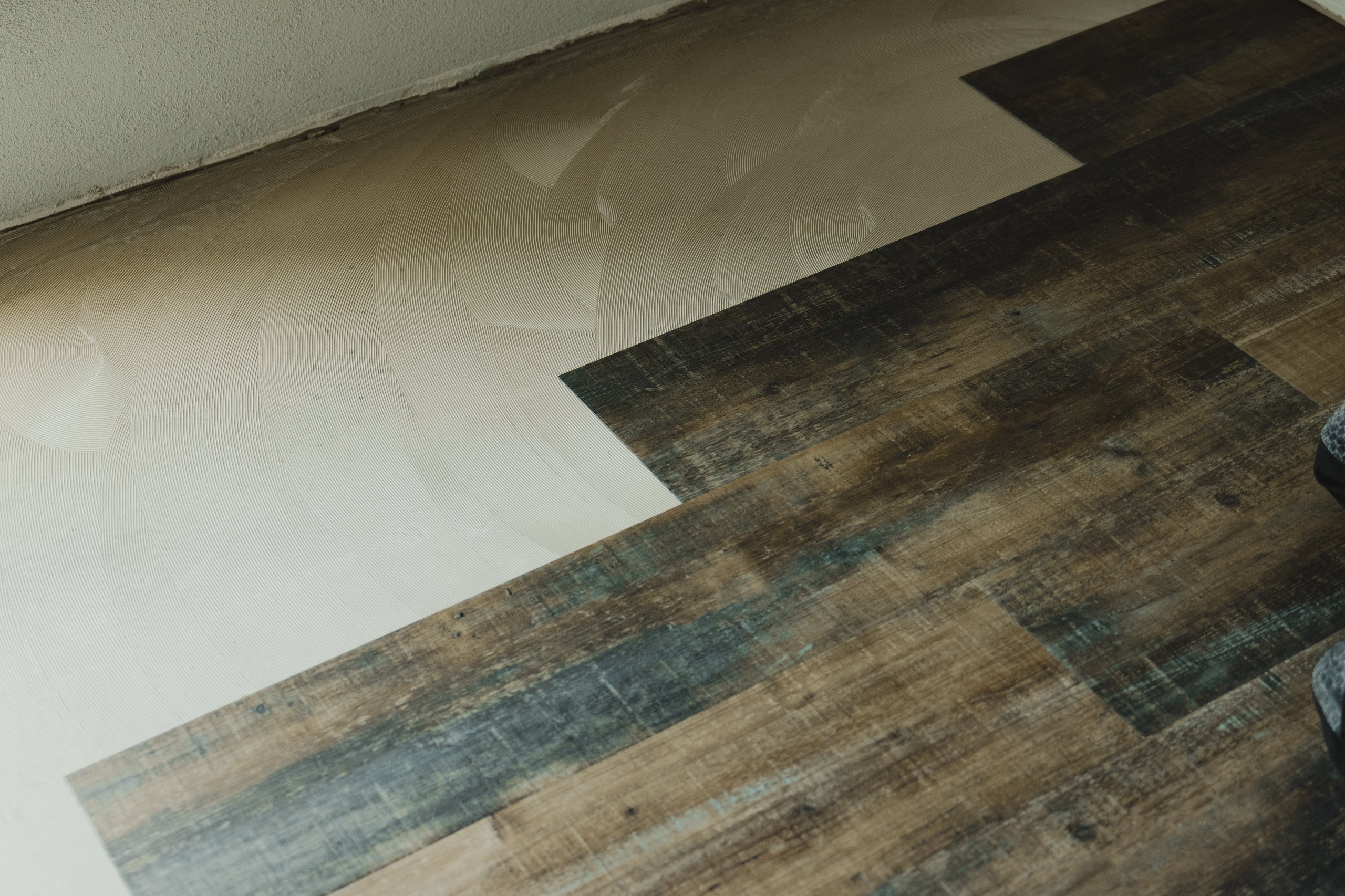 Installing luxury vinyl flooring planks with a textured wood look over a concrete subfloor